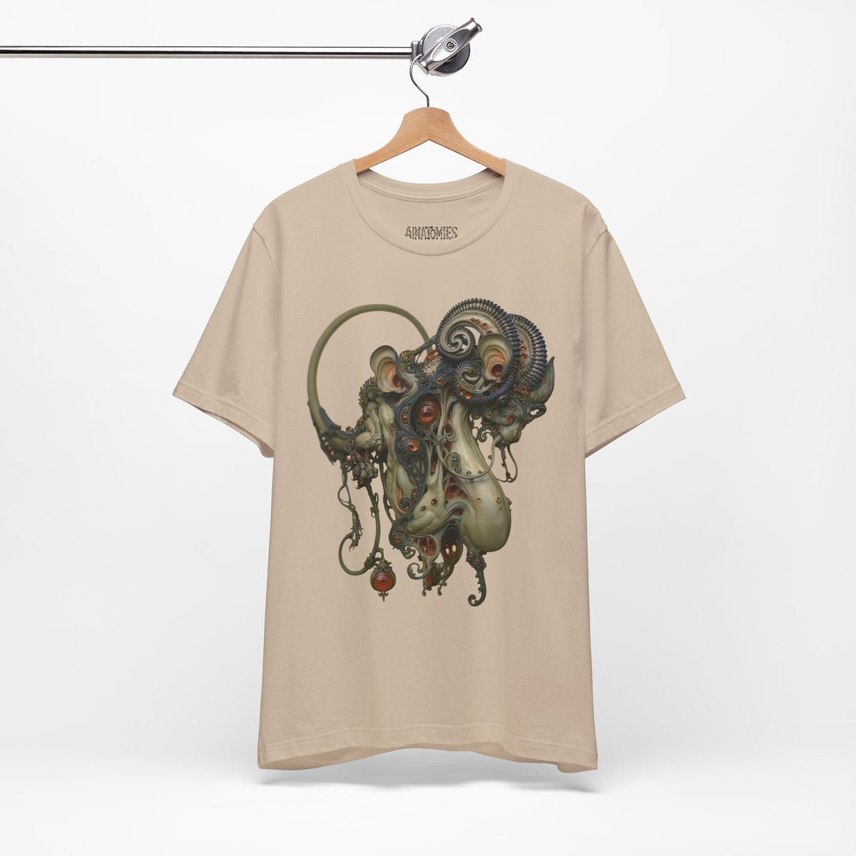 Hanging front view of Before the Light Returns T-Shirt in Tan, featuring an ornate olive and bronze creature with a curled tail.