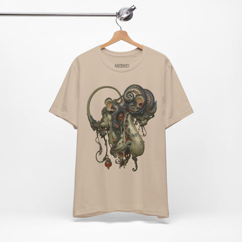 Hanging front view of Before the Light Returns T-Shirt in Tan, featuring an ornate olive and bronze creature with a curled tail.
